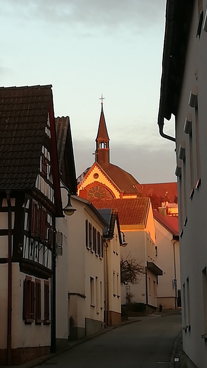 Photo by Michael Schreiber a street lined with white buildings with a church steeple in the background